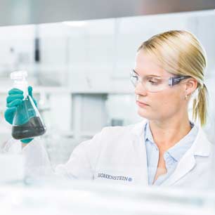 Hohenstein textile testing lab tech holding flask with textile in solution