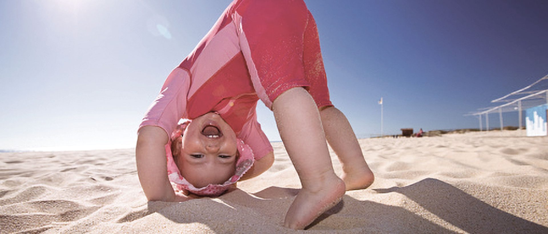 Baby wearing UV clothes and hat on beach